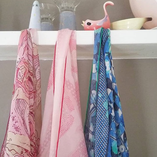 three silk chiffon scarves hanging from a shelf